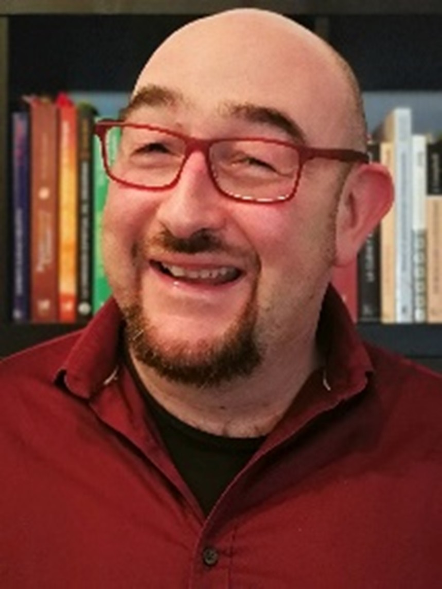 Alain Mullenex sonriendo ante una biblioteca